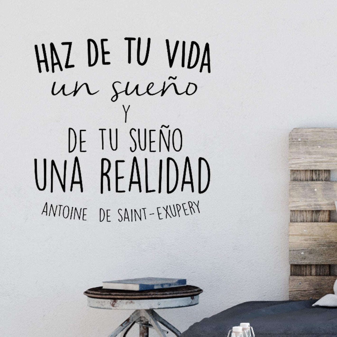 La imagen muestra una pared blanca con varios vinilos decorativos de diferentes diseños y tamaños colocados en ella. Los vinilos incluyen imágenes de animales, frases motivadoras y diseños abstractos en colores vibrantes. Esta imagen muestra cómo los vin